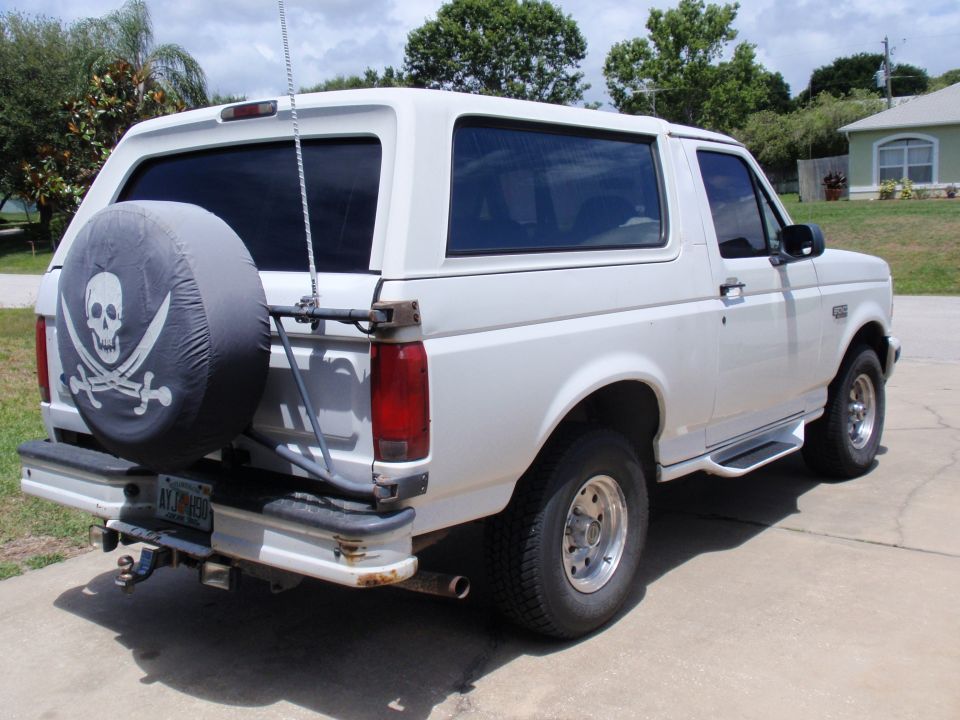 White 1995 Ford Bronco with pirate skull spare tire cover parked on pavement