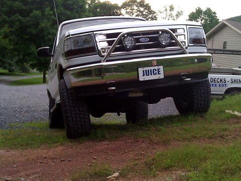 1995 Ford Bronco - This silver Ford Bronco features a chrome bull bar and KC lights, with a custom license plate reading 'JUICE'.