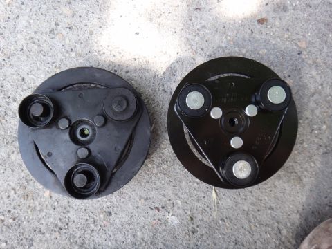 2003 Ford Taurus - Two AC compressor clutch hubs are displayed on a textured concrete background. One hub shows part numbers.