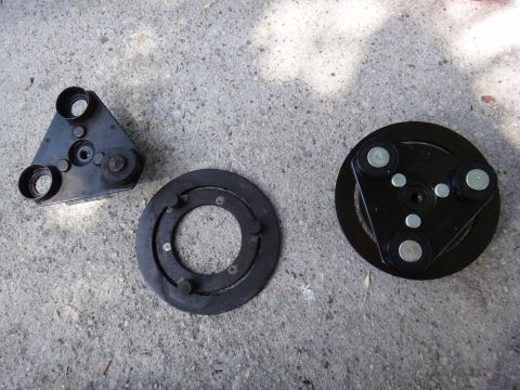 2003 Ford Taurus - Three disassembled parts of an air conditioning clutch are shown on a concrete surface.