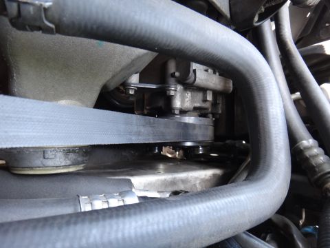 2003 Ford Taurus - A close-up view of the serpentine belt and pulleys within a vehicle's engine compartment.