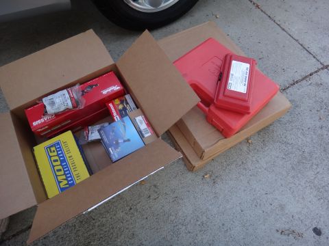 2003 Ford Taurus - Car parts, including Moog chassis components and red tool cases, are laid out on the ground.