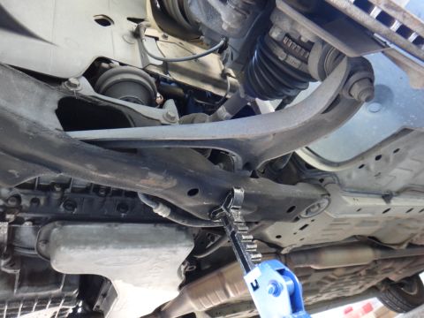 2003 Ford Taurus - Underside view of front suspension components, including the lower control arm and ball joint area, with a jack in place.