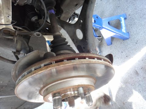 2003 Ford Taurus - Front suspension components including brake rotor and CV axle boot are visible, supported by a jack stand.