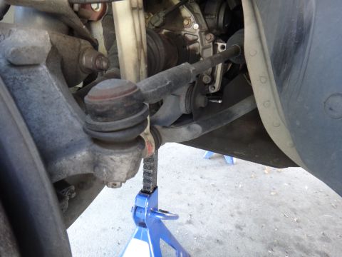 2003 Ford Taurus - The photo shows a close-up view of a vehicle's steering and suspension components, including a tie rod end, with a jack supporting the asse…