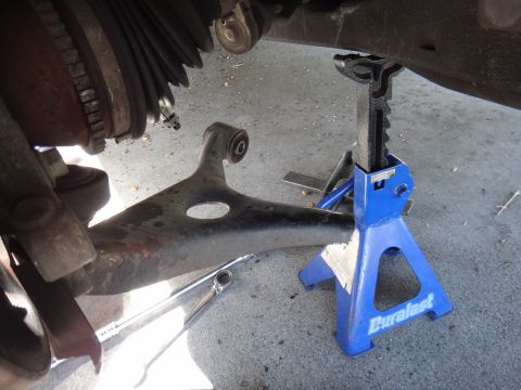 2003 Ford Taurus - Close-up view of a vehicle's lower control arm and ball joint assembly, supported by a blue jack stand.