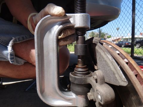 2003 Ford Taurus - A mechanic uses a ball joint press tool on a vehicle's suspension system.
