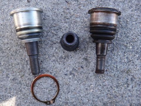 2003 Ford Taurus - Two ball joints and a nut are laid out on a concrete surface, with one appearing significantly more worn than the other.