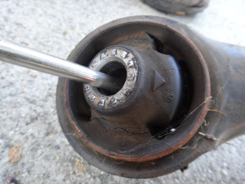 2003 Ford Taurus - A worn suspension bushing with a metal rod inserted, indicating damage and wear on the part.