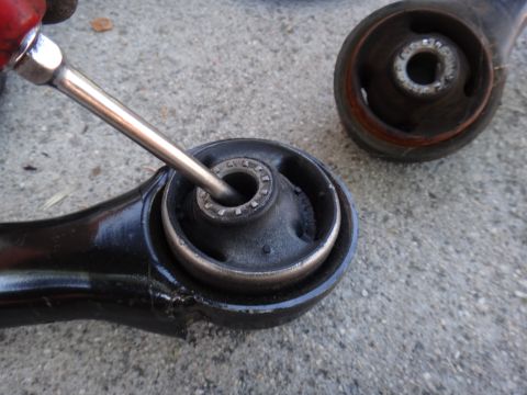 2003 Ford Taurus - A mechanic works on a front lower control arm bushing, likely for replacement or maintenance.