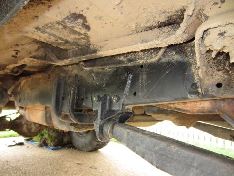 1992 Ford Bronco - A close-up view of the undercarriage reveals the vehicle's suspension and exhaust system, with dirt and grime accumulated on the frame.