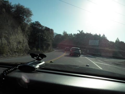 2003 Ford Crown Victoria - Driver POV of a sunlit canyon road bend, a coiled radio microphone mounted on the dash.