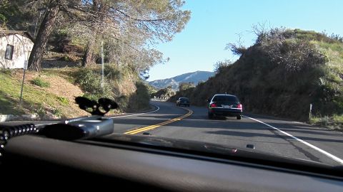 2003 Ford Crown Victoria - POV of a curving hillside road; two dark sedans ahead on the double-yellow two-lane.
