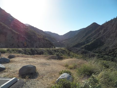 2003 Ford Crown Victoria - Hazy canyon valley framed by ridgelines, with boulders and dry grass in the foreground.