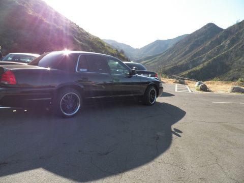 2003 Ford Crown Victoria - Side-rear angle of a lowered black sedan in a paved mountain pullout, canyon in background