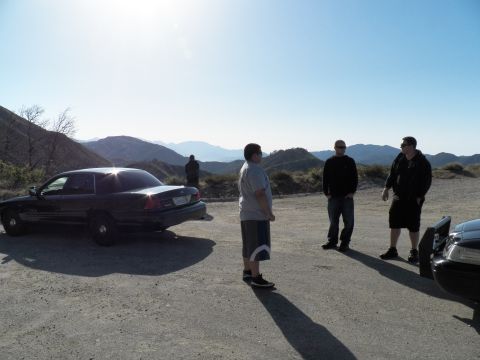 2003 Ford Crown Victoria - Group of men beside a backlit black sedan with mountain range behind them