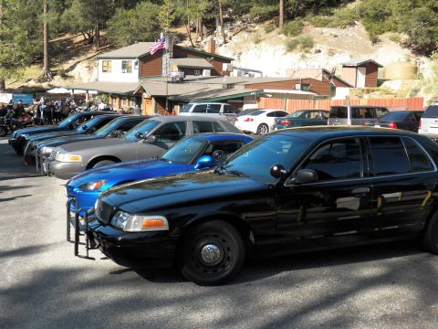 2003 Ford Crown Victoria - Close view of a black Ford cruiser, blue S2000 alongside near a lodge with flag.