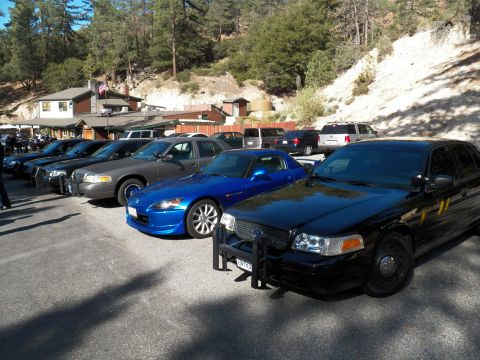 2003 Ford Crown Victoria - Blue Honda S2000 wedged between full-size sedans at a forest lot.