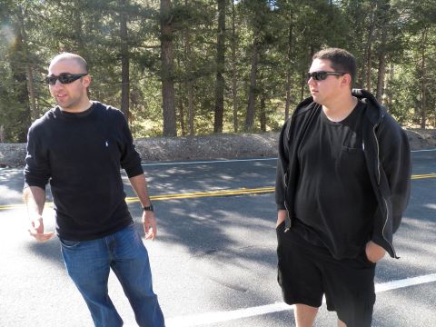 2003 Ford Crown Victoria - Two men in sunglasses stroll along a pine-lined mountain road.
