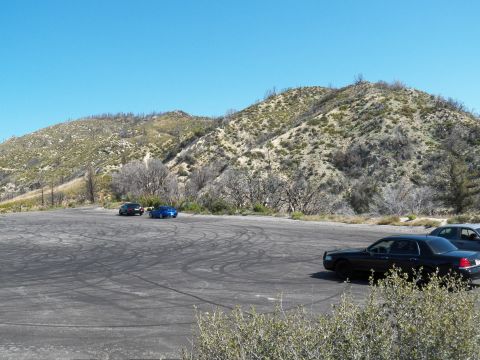 2003 Ford Crown Victoria - Black sedan in foreground with two distant cars on a wide mountain pullout