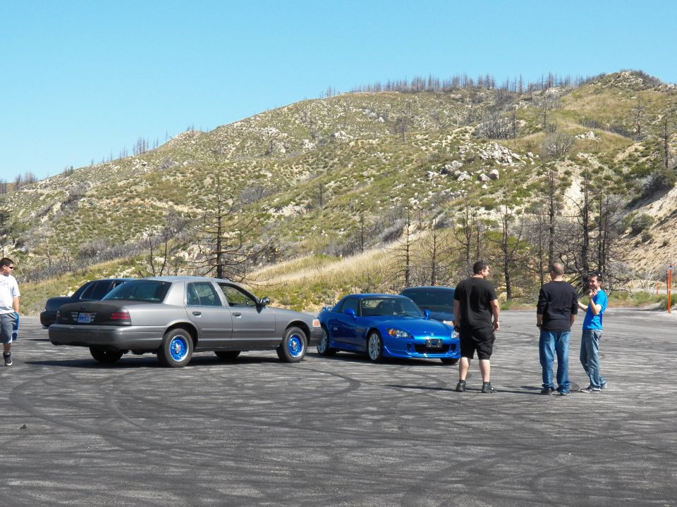 Silver sedan with blue wheels and blue Honda S2000 with men standing by