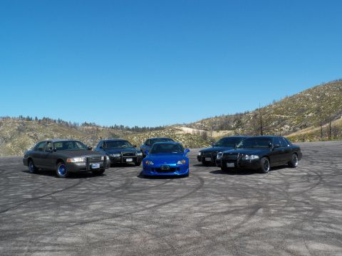 2003 Ford Crown Victoria - Police-style Crown Victoria sedans with blue rims beside a blue Honda roadster.