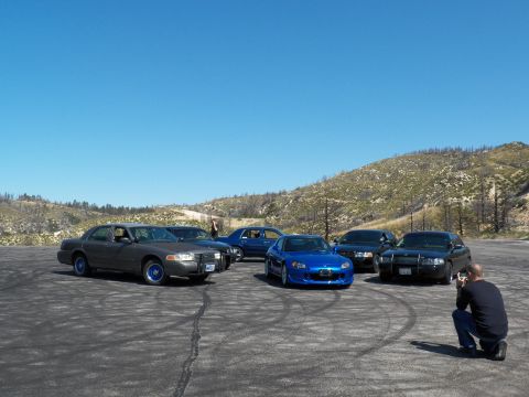 2003 Ford Crown Victoria - Photographer crouches to shoot a blue roadster lined up with grey and black sedans.