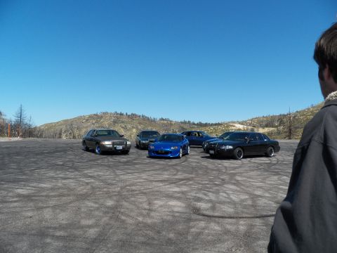 2003 Ford Crown Victoria - Wide view of several vehicles gathered on a mountain pullout with a bystander in foreground