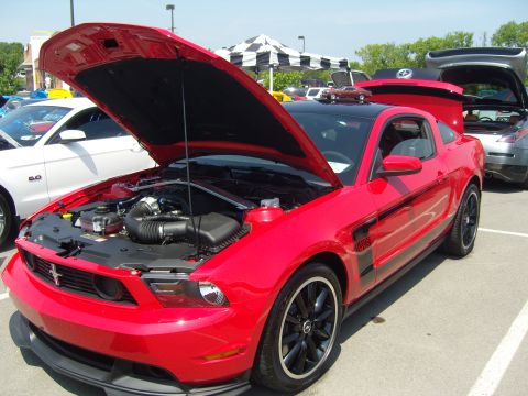 2007 Ford Mustang - Red Ford Mustang Boss 302 on display with hood open, parked next to another vehicle.