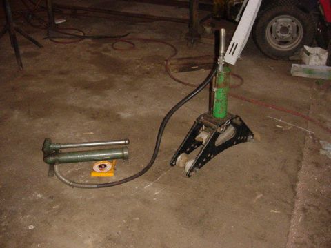 1992 Ford Bronco - A green grease gun and a black jack stand are visible on a concrete floor, with a tire in the background.