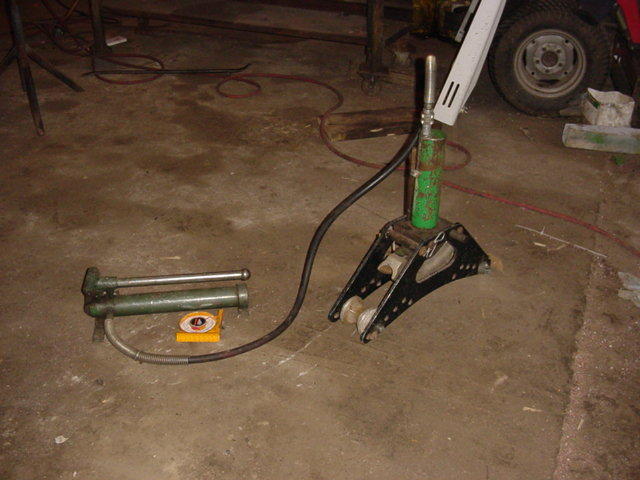 Green grease gun and black jack stand on concrete floor