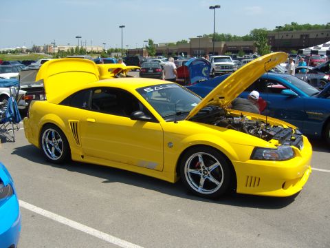 2007 Ford Mustang - A yellow 2007 Ford Mustang is displayed with its hood and trunk open at a car show.