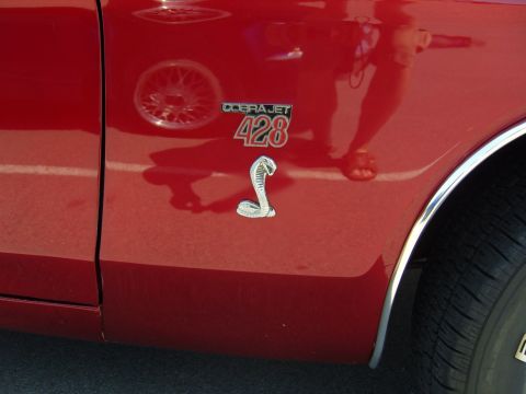 2007 Ford Mustang - Close-up of a red car fender displaying the distinctive Cobra Jet 428 badging and a coiled snake emblem.
