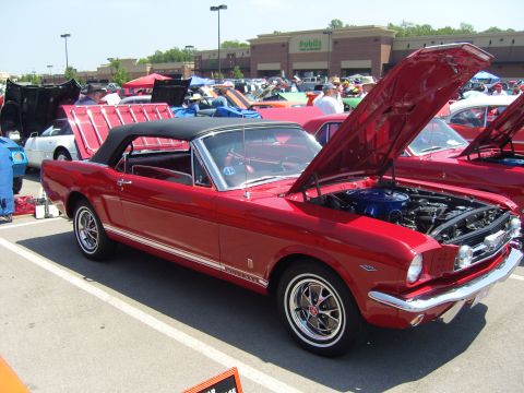 2007 Ford Mustang - A red convertible classic car is displayed with its hood open at a car show, surrounded by other vehicles.