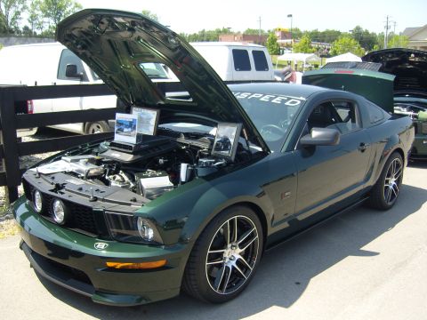 2007 Ford Mustang - A dark green 2007 Ford Mustang is displayed with its hood open, revealing the engine and custom rims.