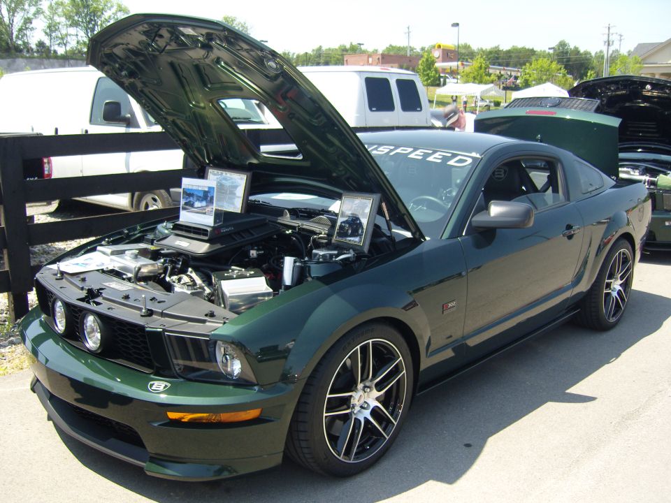 Dark green 2007 Ford Mustang with hood open, showing engine and custom wheels
