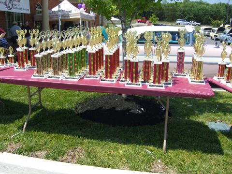 2007 Ford Mustang - A display of trophies sits on a table, with several cars visible in the background at an outdoor event.
