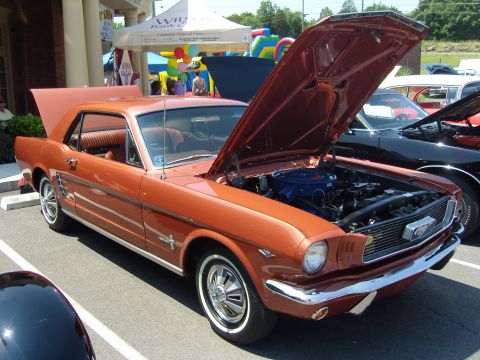 2007 Ford Mustang - This classic orange 1965 Ford Mustang coupe is displayed with its hood open, revealing the engine bay.