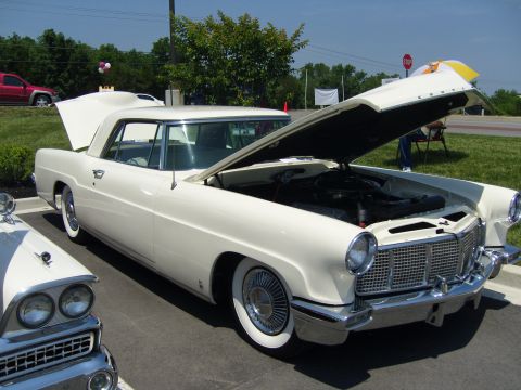 2007 Ford Mustang - White 1956 Lincoln Continental at a car show, hood and trunk open.