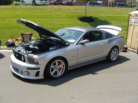 2007 Ford Mustang - A silver Ford Mustang GT is parked with its hood and trunk open, next to a portable toilet.