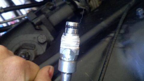 1978 Ford Bronco - A hand holds a metal fitting that appears to be part of a hose or line.