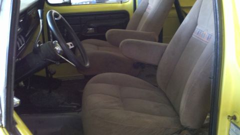 1978 Ford Bronco - The interior of a vehicle features plush bucket seats and a steering wheel, with a yellow exterior visible.