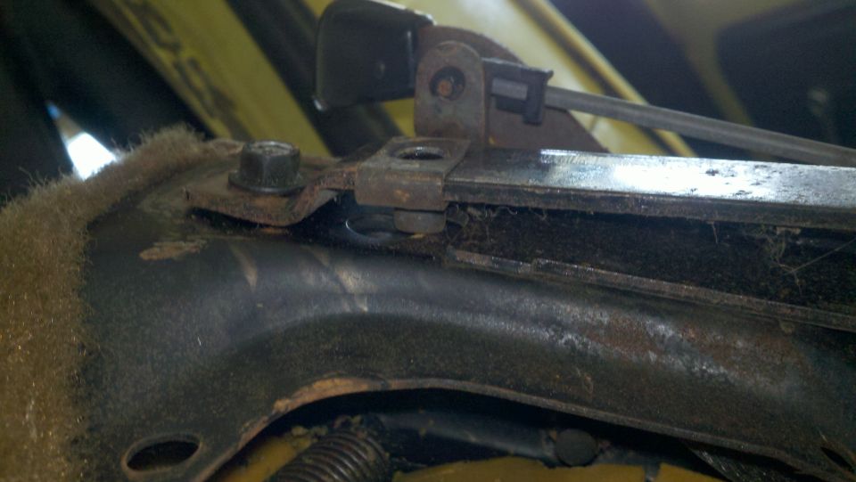 Close-up of a rusty seat adjustment mechanism with visible bolts and springs