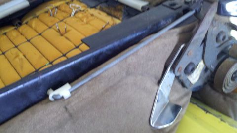 1978 Ford Bronco - Close-up of a car's interior seat mechanism, showing foam padding and a chrome handle.