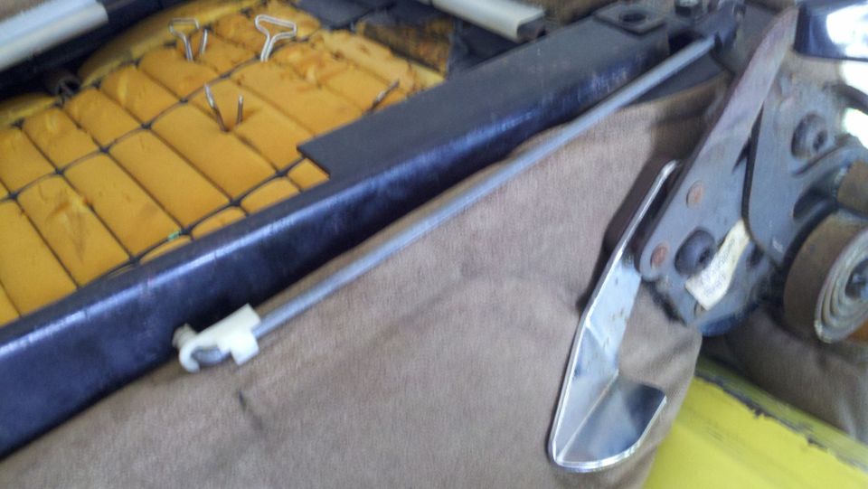 Car seat mechanism with yellow foam padding and brown fabric. Chrome handle visible
