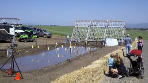 1978 Ford Bronco - An outdoor obstacle course is set up with a mud pit and climbing structure, with vehicles and people nearby.