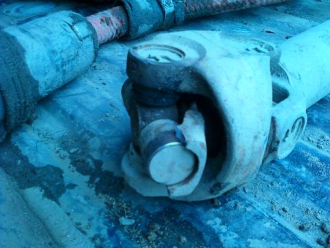 1990 Ford Bronco - This image shows a close-up of a vehicle's driveshaft universal joint, with visible dirt and rust.