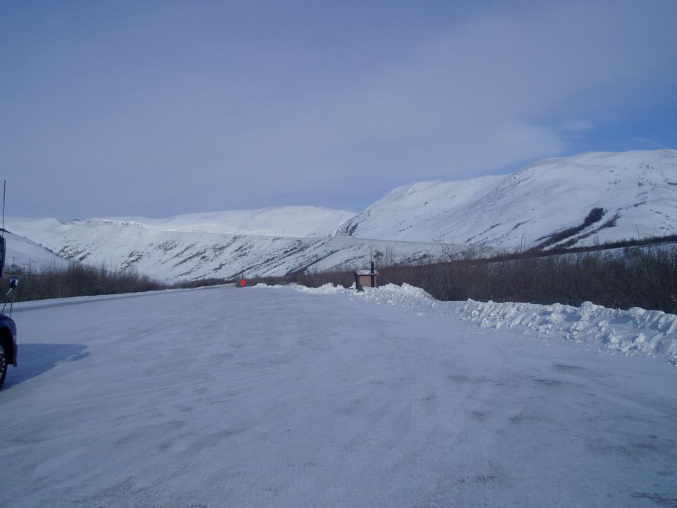 Snowy landscape with a truck parked on the side of a road