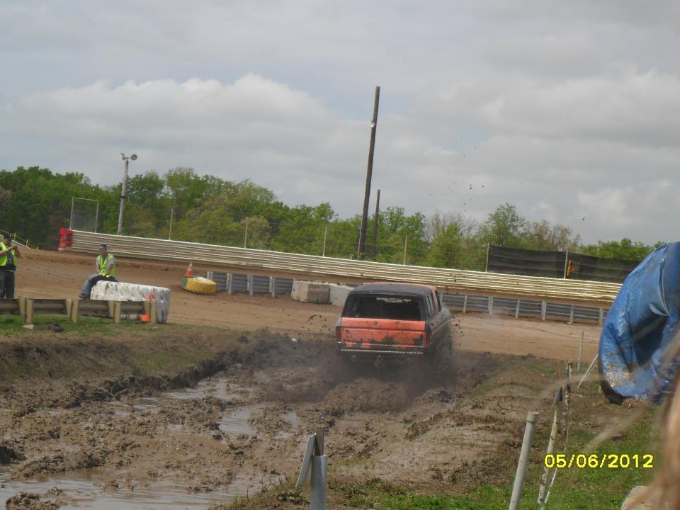 Orange 1978 Ford Bronco driving through mud, rear view