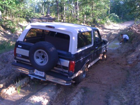 1992 Ford Bronco - This 1992 Ford Bronco is navigating a muddy trail, with its rear end partially submerged in the mire.